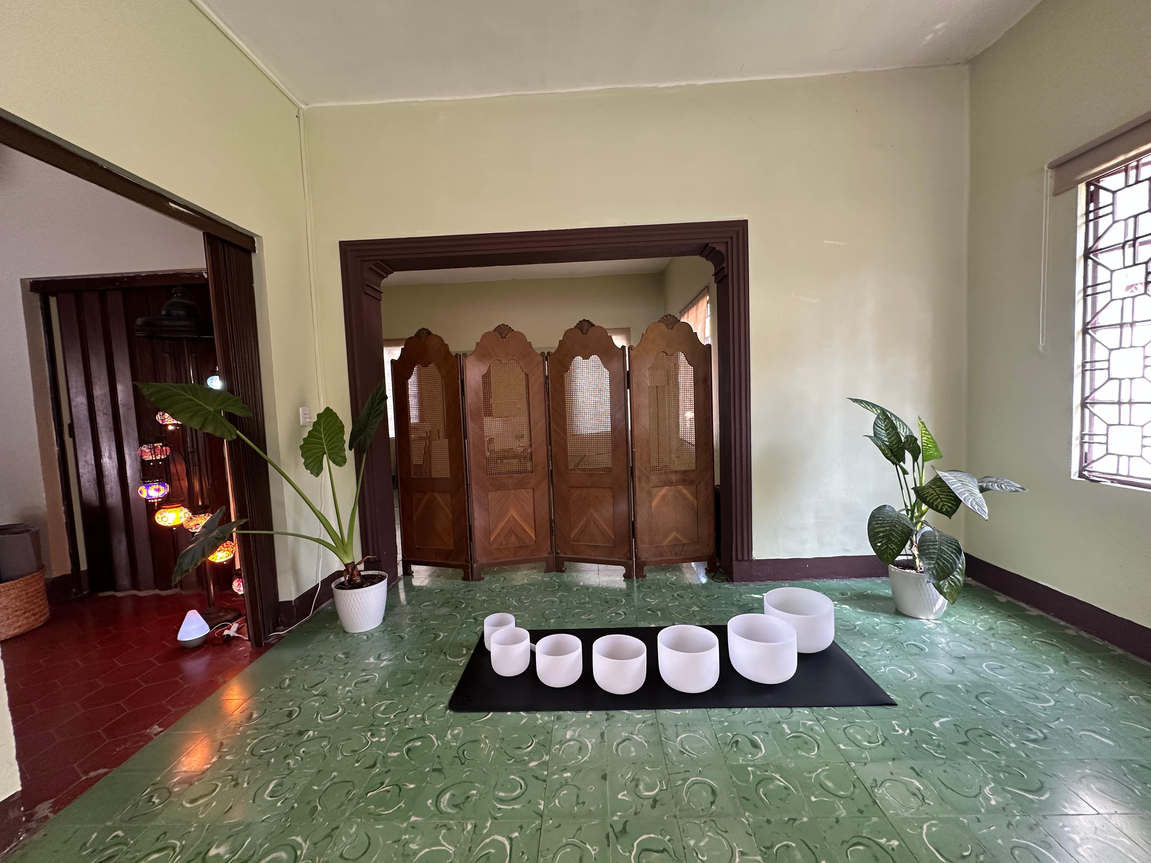 Sala de Casa Zenia: cuencos de cristal alineados sobre el tapete, entre plantas y el arco de madera.